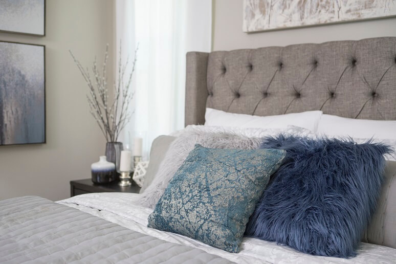 Winter solstice themes bedroom with fluffy pillows and gray and white colors all around.