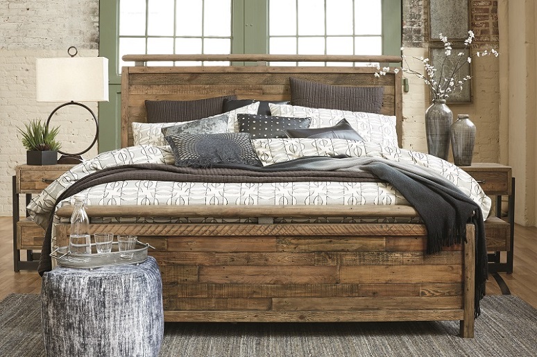 Sommerford brown wood bedroom set with a pouf at the foot of the bed and two nightstands.