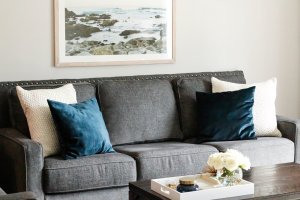 gray sofa with blue velvet pillows decorated on top and a coffee table with a tray on top.