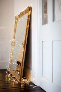 A golden mirror with lights wrapped around it.