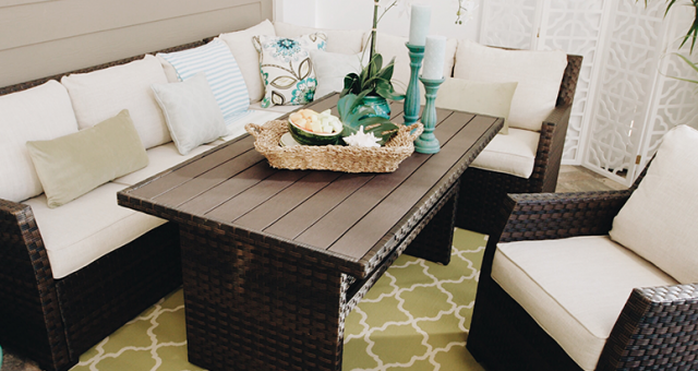 A beautiful covered patio with a neutral colored outdoor sectional decorated with sea foam greens and blues.
