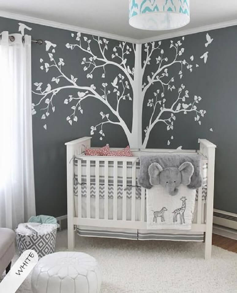 Nursery with a tree decal behind the crib.