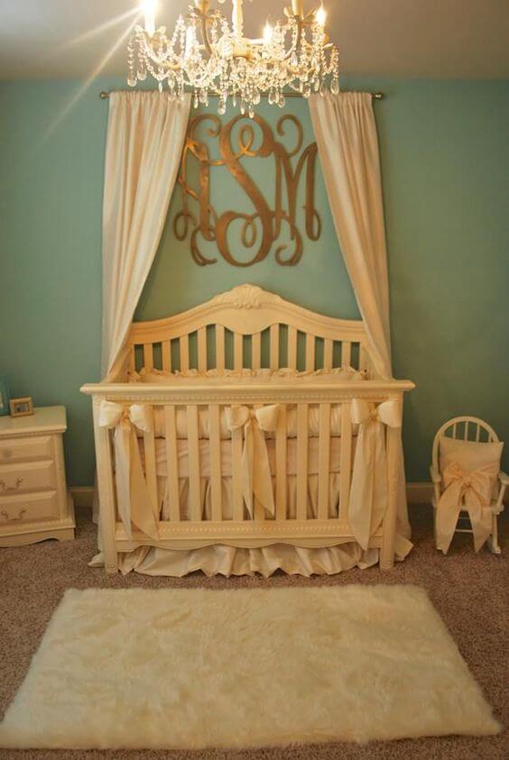 Nursery with drapes over the crib and a chandelier with a monogram also above the crib.