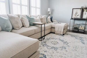 Room shot of nadias sectional with pilows on top and the windows open behind the sectional.