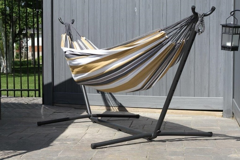 Stripped hammock on a back patio connected to a hammock stand. 