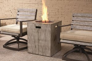 A small square firepit between two outdoor chairs.