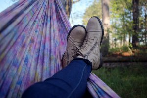 Photograph of a person in a hammock relaxing with their legs crossed while overlooking the wilderness.