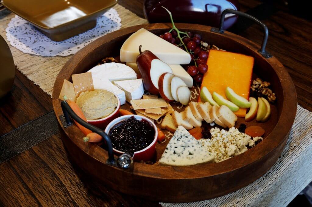 Home Accents Tray, a circular wooden platter made of Mango Wood, displayed with assorted cheeses and crackers.