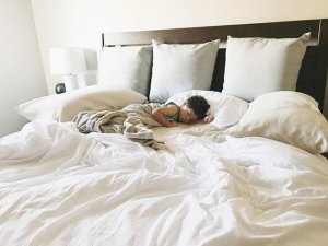 child sleeping on bed with white sheets