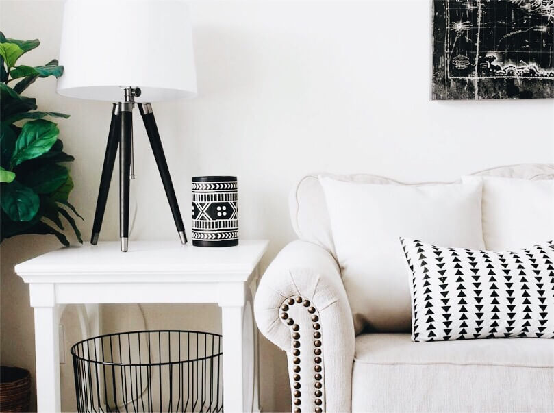 beige couch with white an black pillow next to white nightstand