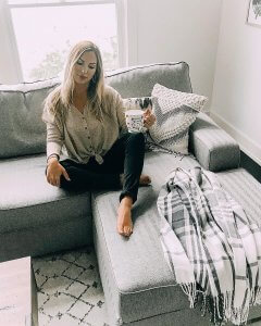 woman sitting on gray couch with coffee