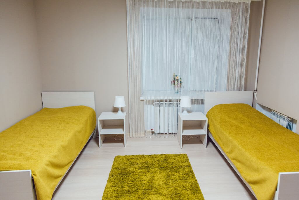 small dorm room with yellow sheets and rug