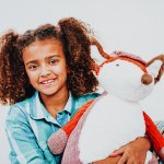 young girl on bed holding bear